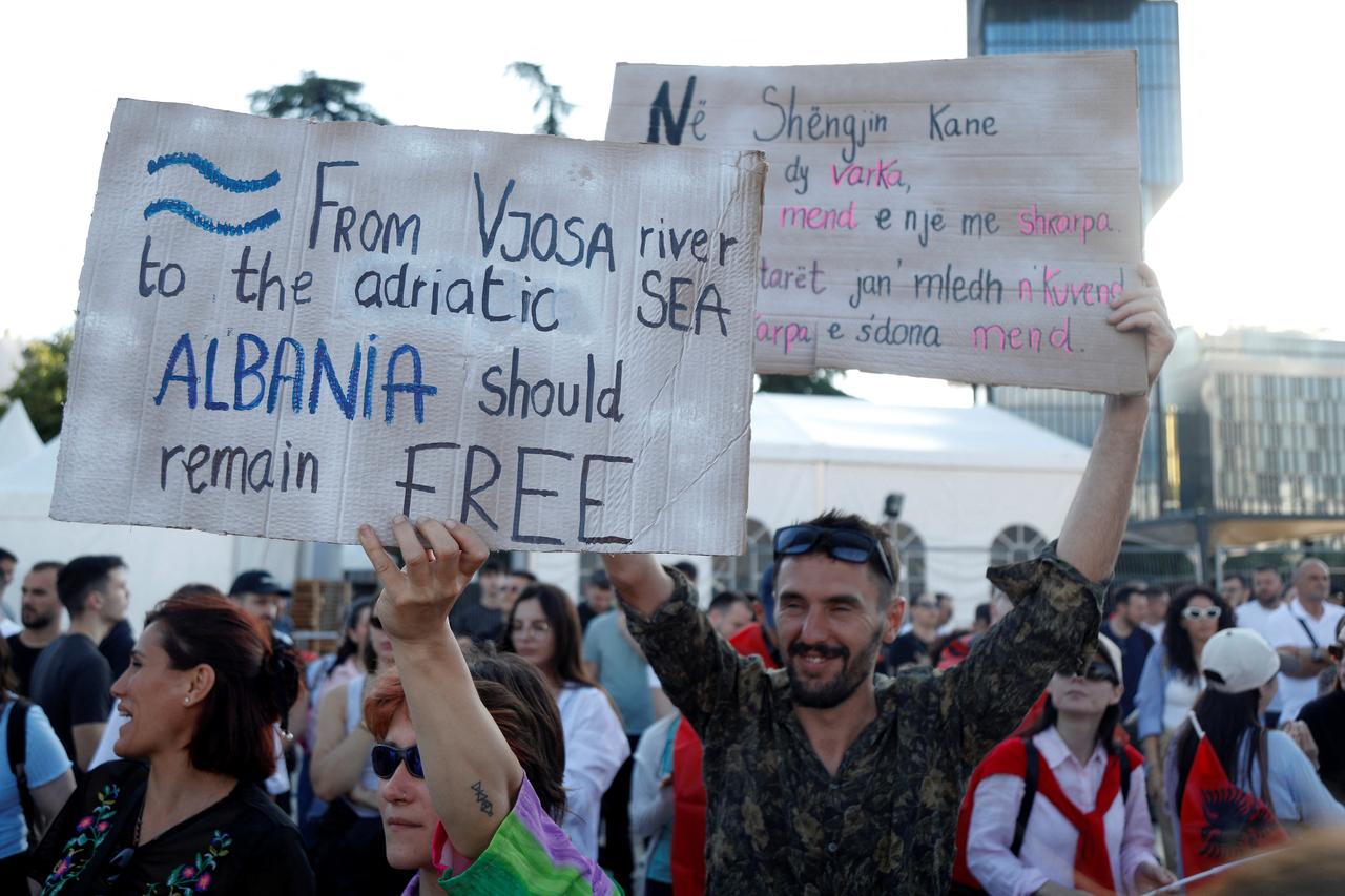A demonstrator (L) holds a placard reading "From Vjosa River to the Adriatic Sea - Albania should remain free" as protestors gather in front of Albania's Prime Minister's Office during the 4th day of demonstration against the construction of a luxury resort near a protected natural area, in Tirana on June 4, 2026. (AFP Photo)