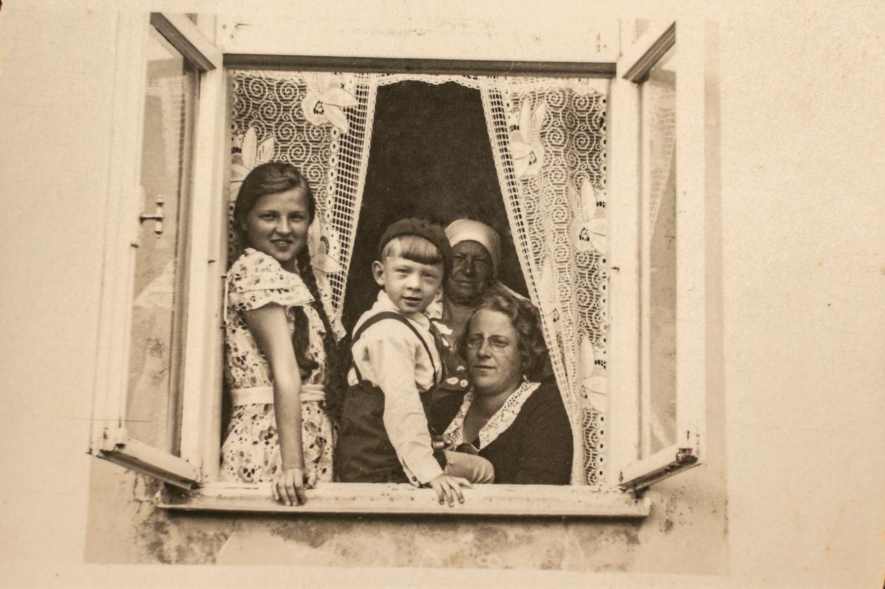 A family sits together on a windowsill in Latvia, circa 1930s. (Adobe Stock Photo)