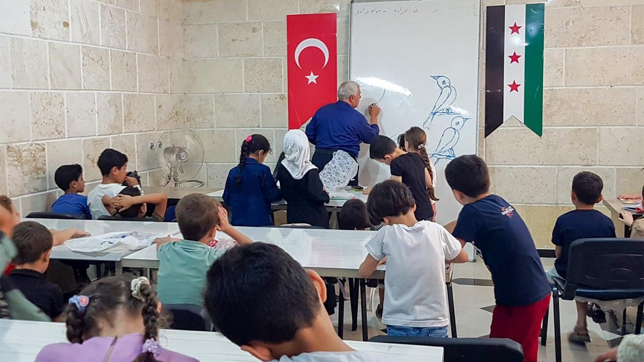 An instructor guides young Syrian students through an art lesson at an Anatolian Cultural Center summer school organized by the Bulbulzade Foundation.