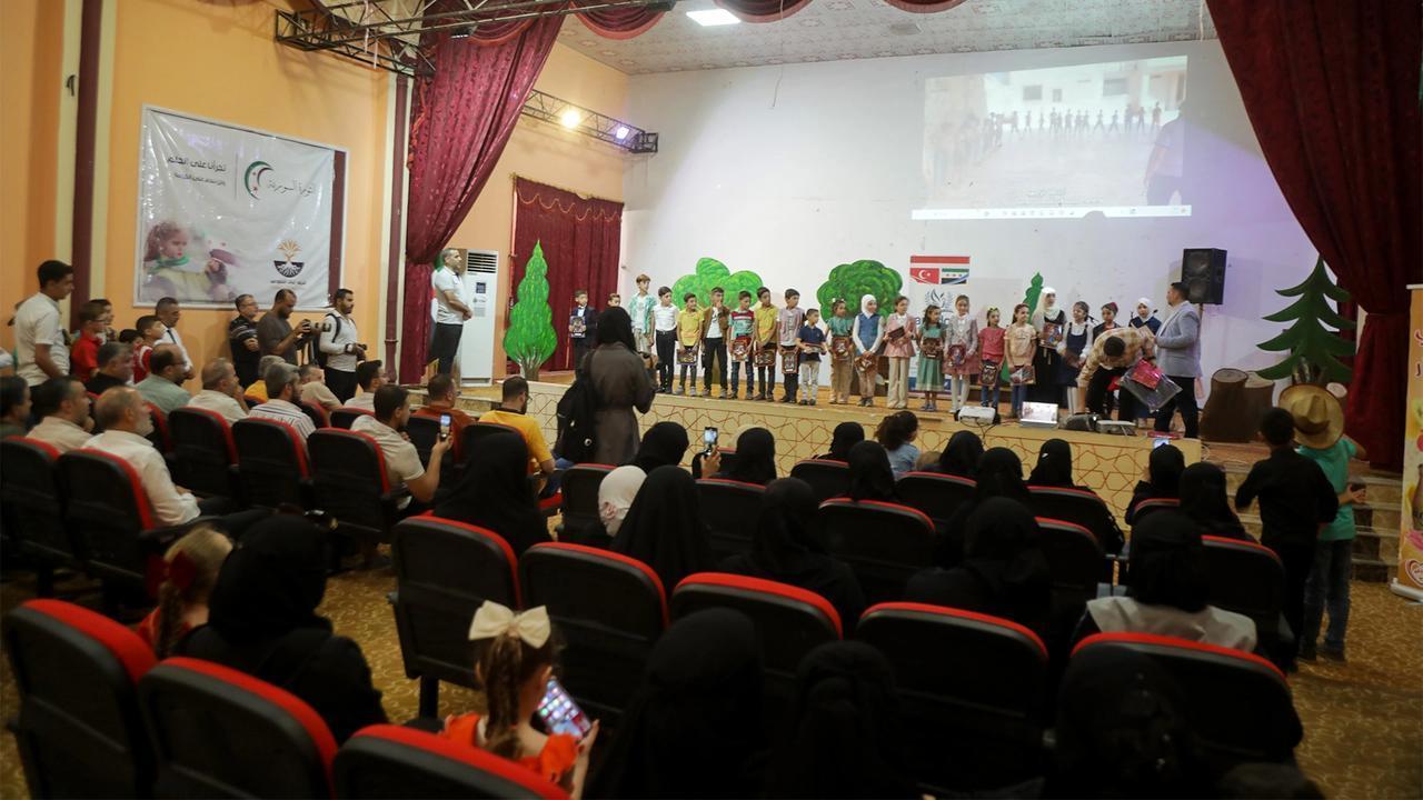 An auditorium audience watches a stage presentation at an Anatolian Culture Center event in Syria.