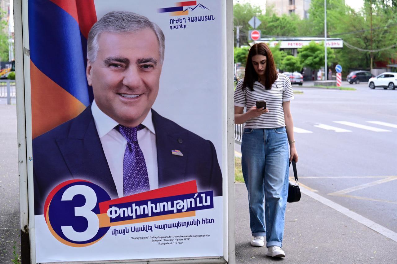 A woman walks past a campaign poster of Strong Armenia, the party of billionaire Russian-Armenian businessman Samvel Karapetyan, in Yerevan, June 4, 2026. (AFP Photo)
