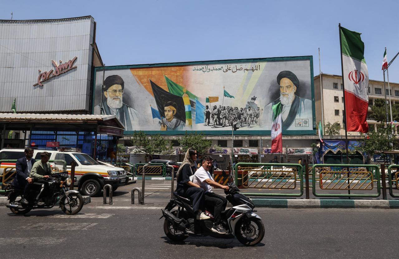 Iranians ride past a banner depicting Iran's late supreme leader Ruhollah Khomeini (R), his successor, the late Ali Khamenei (L), in Enghelab Square in Tehran on June 3, 2026. (AFP Photo)