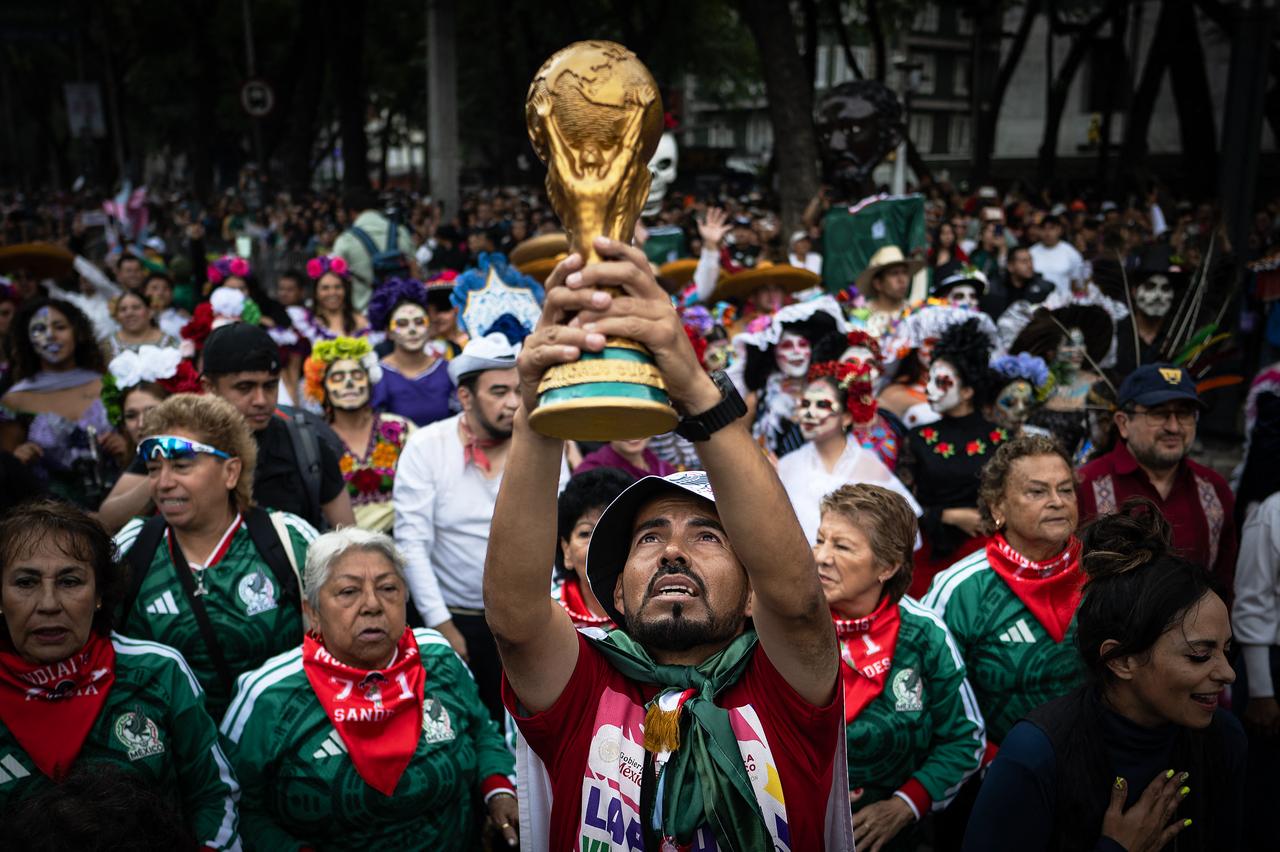 A man holds up a replica of a World Cup trophy before the start of a Guinness World Record attempt for the world’s largest Mexican Wave in Mexico City on June 6, 2026. (AFP Photo)