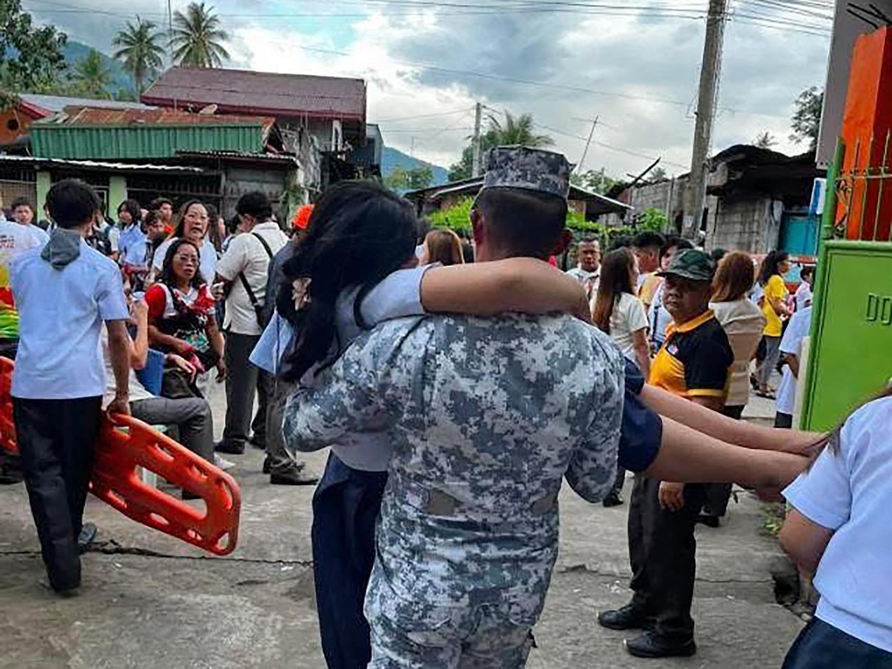 This handout photo taken and released on June 8, 2026 by the Philippine Coast Guard shows a Coast Guard serviceman carrying an earthquake-affected student in Sta Cruz, Davao del Sur. (Photo by Handout/Philippine Coast Guard(PCG)/AFP)