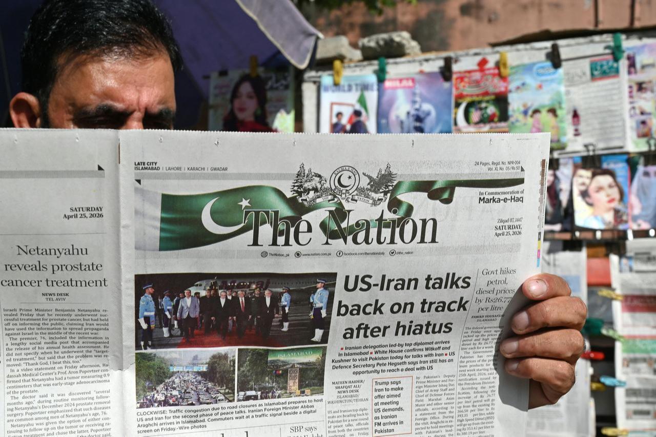 A man reads a newspaper at a roadside stall in Islamabad on April 25, 2026. (AFP Photo)