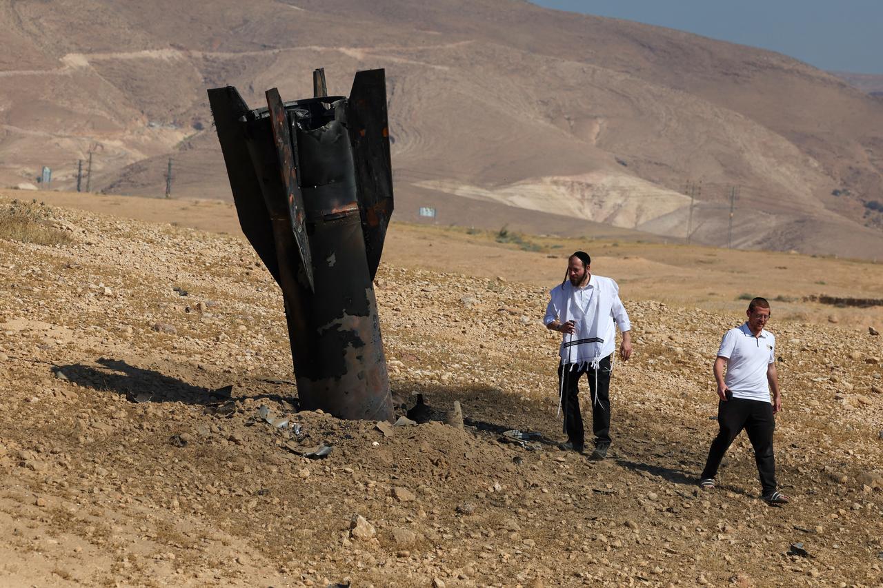 Two men examine a fallen rock half-buried in the ground on the outskirts of Jericho on June 8, 2026, following Iranian and Iran-backed Houthi rebel attacks. (AFP Photo)