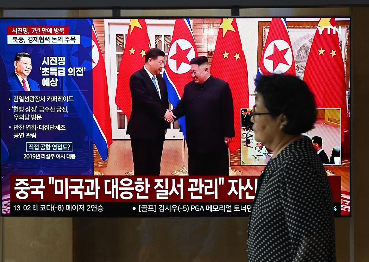 A woman walks past a television screen showing a news broadcast with file footage of the 2019 meeting between China's President Xi Jinping and North Korean leader Kim Jong Un, at a train station in Seoul, South Korea, June 8, 2026. (AFP Photo)