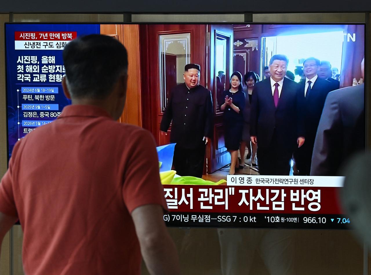 A man walks past a television screen showing a news broadcast with file footage of the 2019 meeting between China's President Xi Jinping and North Korean leader Kim Jong Un, at a train station in Seoul, South Korea, June 8, 2026. (AFP Photo)