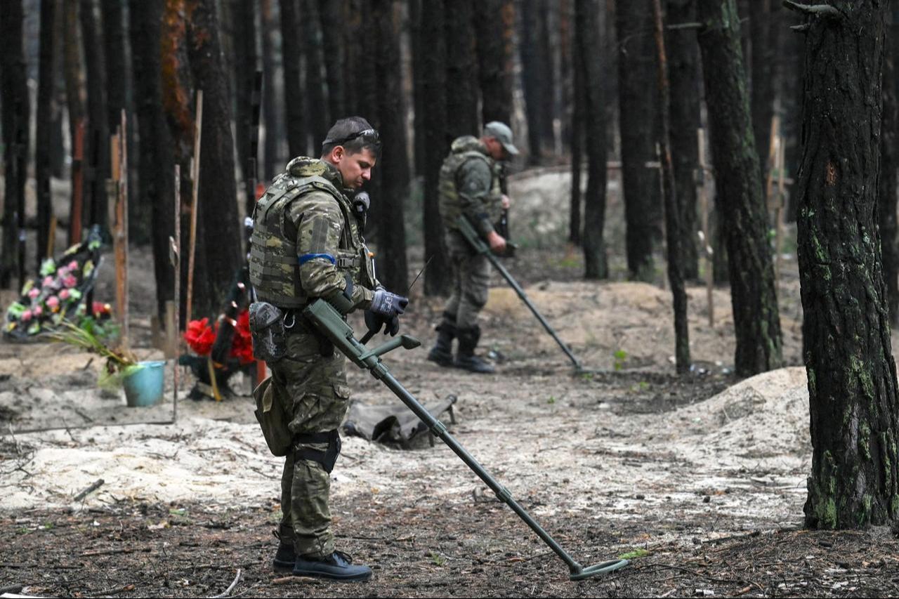 Ukrainian servicemen search for land mines at a burial site in a forest on the outskirts of Izyum, eastern Ukraine, in 2022. (AFP Photo)
