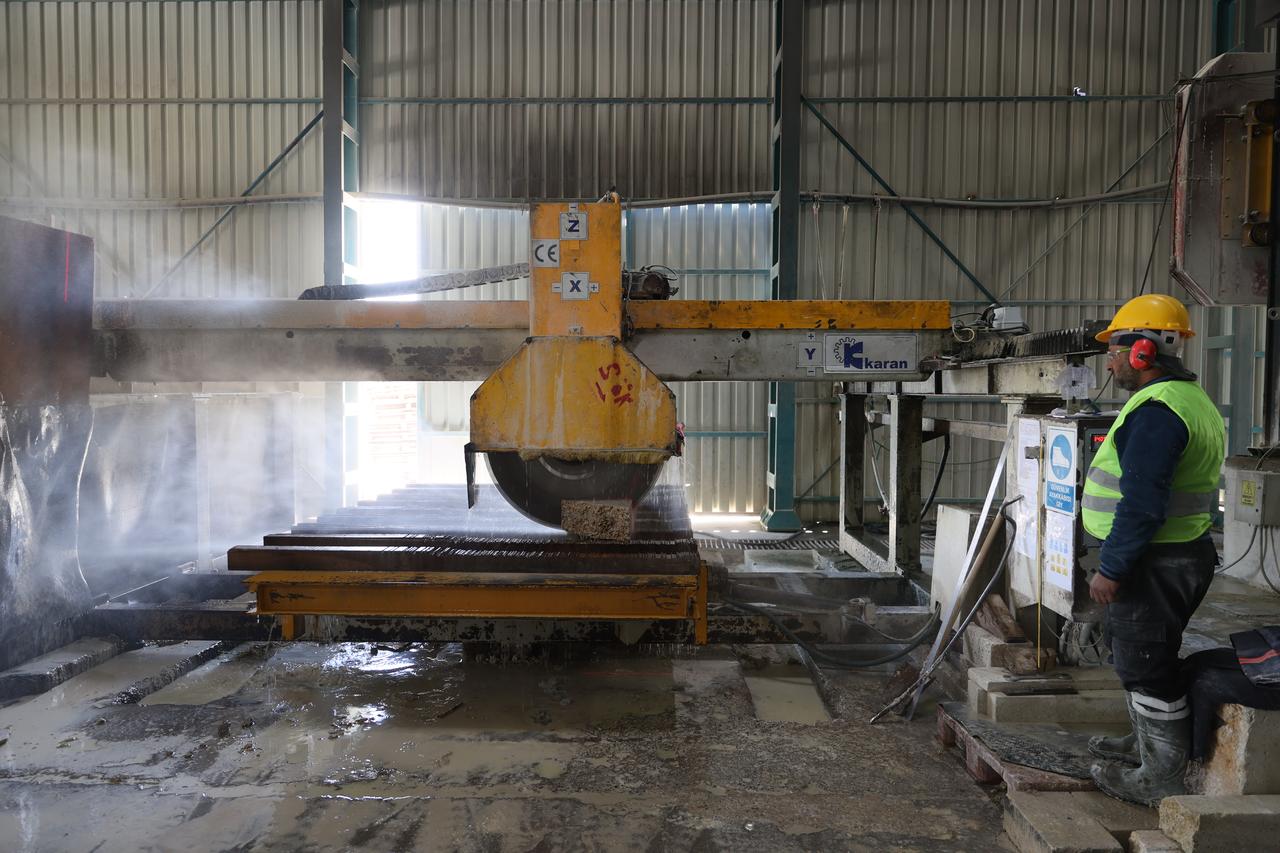 A worker operates a stone-cutting machine as kufeki stone blocks are prepared for restoration projects in Türkiye. (AA Photo)