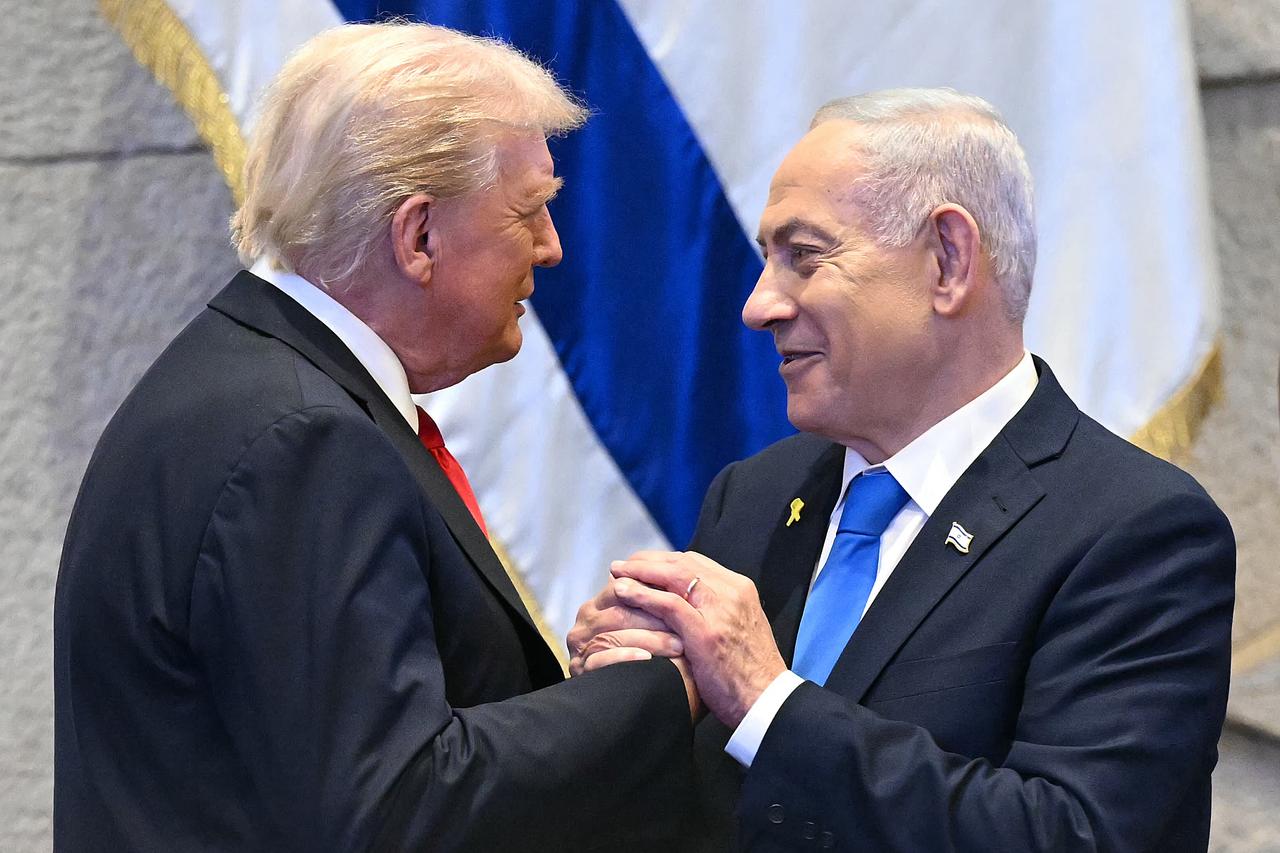 US President Donald Trump (L) holds hands and speaks with Israeli Prime Minister Benjamin Netanyahu at the Israeli parliament, the Knesset, in Jerusalem, Oct. 13, 2025. (AFP Photo)