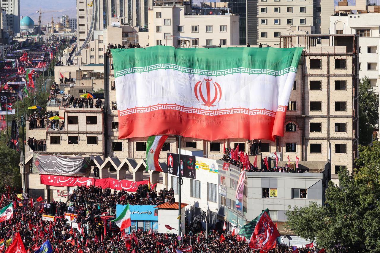 A massive flag of Iran is seen unfurled on the facade of a building as crowds of mourners attend a funeral procession for Iran's slain supreme leader Ali Khamenei and members of his family, before he is buried at the Shrine of Imam Reza, in Mashhad, July 9, 2026. (AFP Photo)