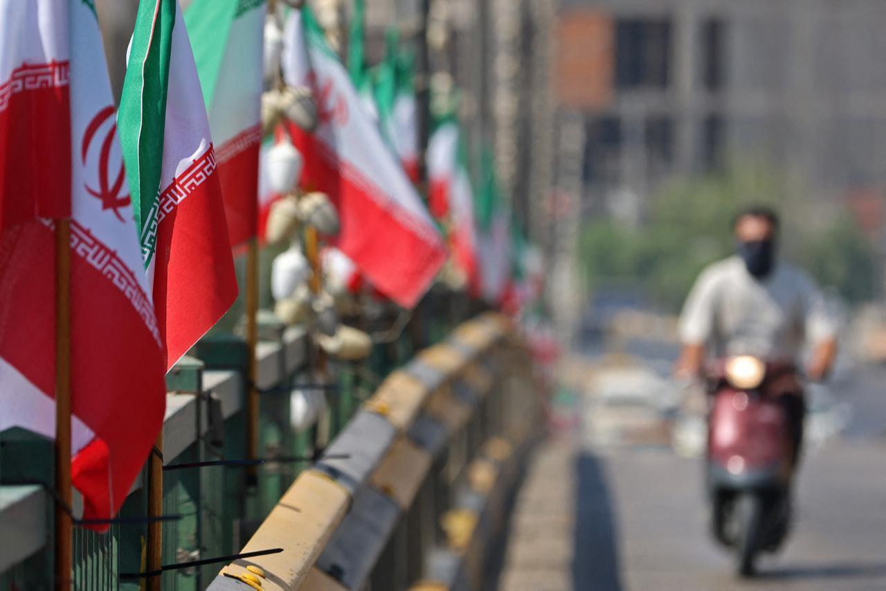 A motorist drives past Iranian flags installed along a street, a day before the funeral procession of Iran's slain supreme leader Ali Khamenei in Karbala, July 7, 2026. (AFP Photo)
