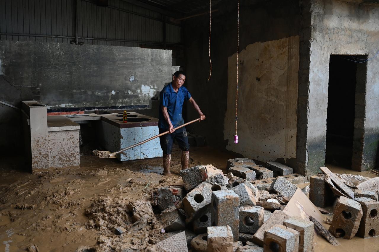 A man clears mud from a kitchen area of a house which was flooded when the Liulan reservoir collapsed on July 6, in Liulan village in Hengzhou city, China, July 8, 2026. (AFP Photo)