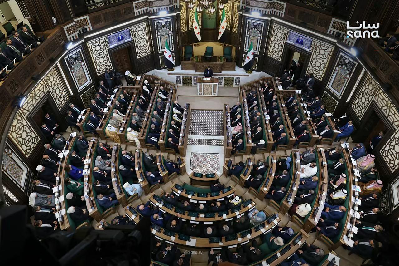 This handout picture taken and released by the official Syrian Arab News Agency (SANA) on July 12, 2026 shows Syria's President Ahmed al-Sharaa (top, C) speaking during the first meeting of Syria's new transitional parliament in Damascus. (Photo by SANA/AFP)