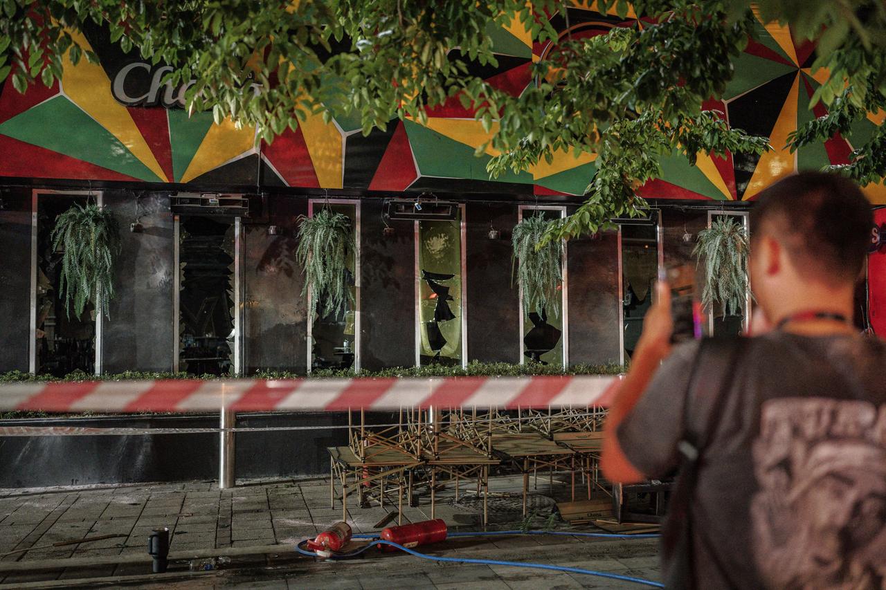 People take photos of the fire-damaged bar after a massive fire engulfed a bar in Bangkok, early on July 13, 2026. (AFP Photo)