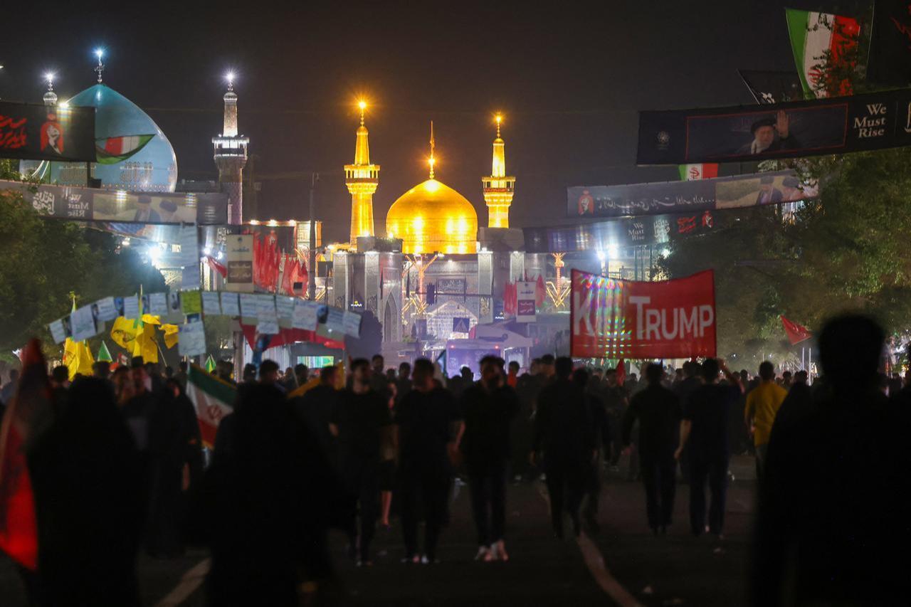 Mourners walk past an anti-US banner (R) as they arrive to attend the funeral of slain Iranian leader Ali Khamenei in Mashhad, July 9, 2026. (AFP Photo)