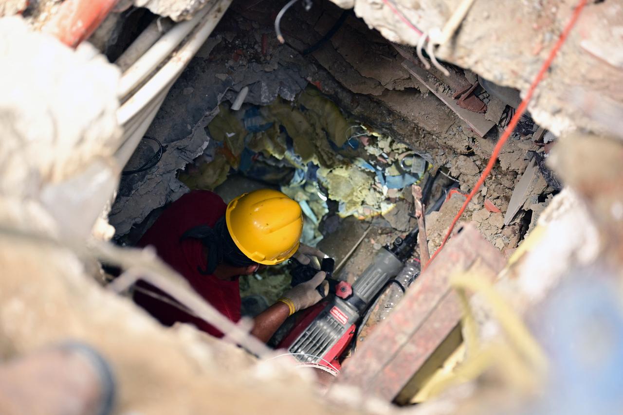 A man works to remove debris from a collapsed building in an attempt to recover the bodies of his loved ones in Caraballeda, La Guaira state, Venezuela, on July 12, 2026, following twin earthquakes that struck the region. (AFP Photo)