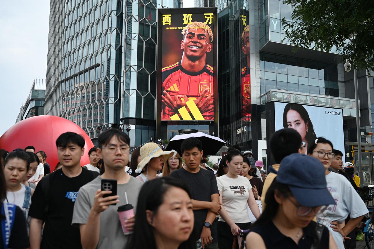 People wait to cross a road near an electronic screen advertisement featuring Spain’s Lamine Yamal, in Beijing on July 12, 2026. (AFP Photo)