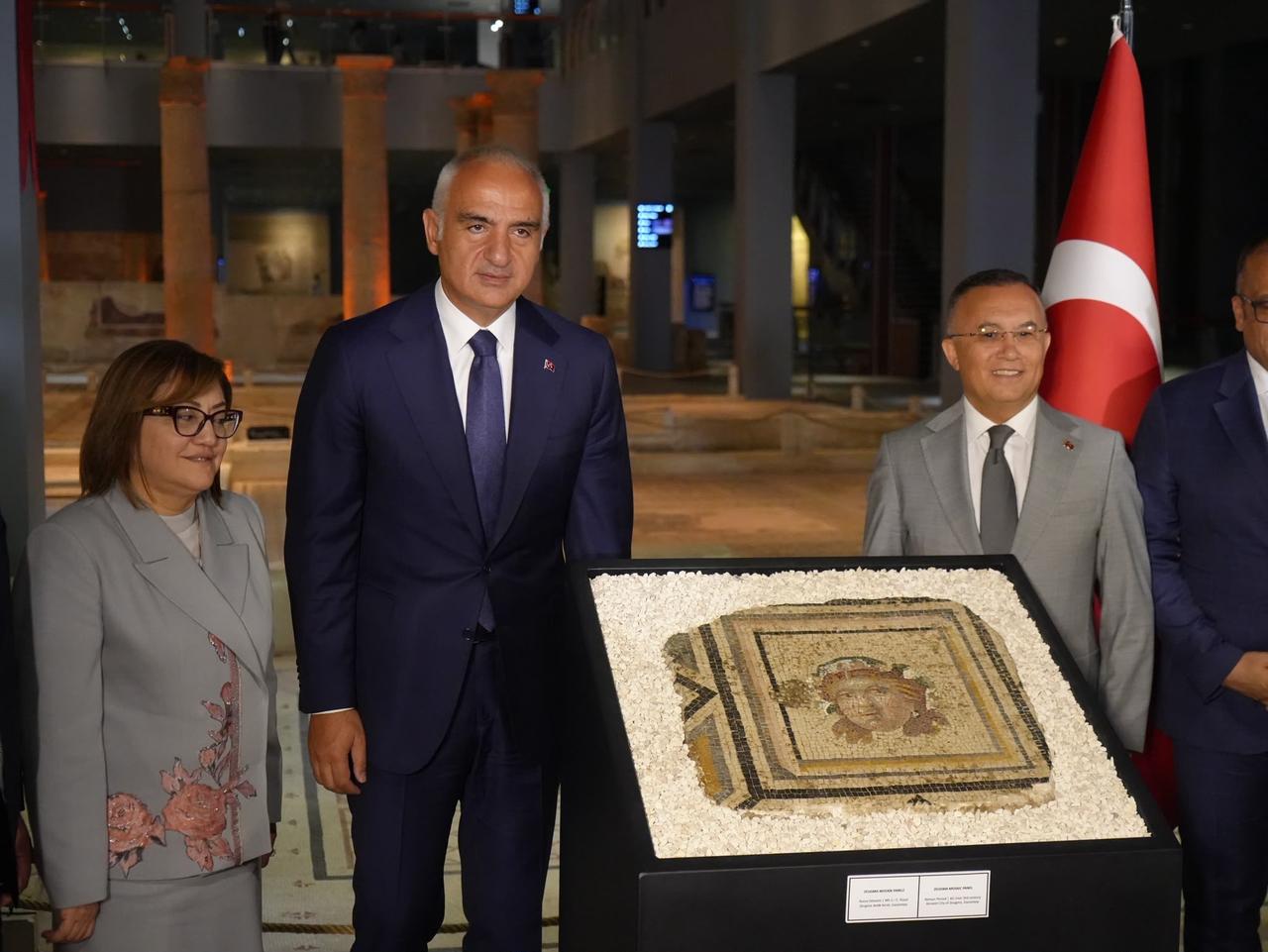 Türkiye’s Culture and Tourism Minister Mehmet Nuri Ersoy (C), Gaziantep Metropolitan Mayor Fatma Sahin (L) and Gaziantep Governor Kemal Ceber (R) stand beside the newly returned 13th panel of the Zeugma mosaic during a handover ceremony at the Zeugma Mosaic Museum in Gaziantep, Türkiye, July 14, 2026. (IHA Photo)
