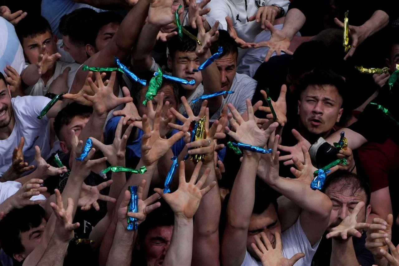 Thousands of hands reach into the air in a struggle to catch foil-wrapped pieces of macun scattered from the heights of the historic Sultan Mosque. (Adobe Stock Photo)