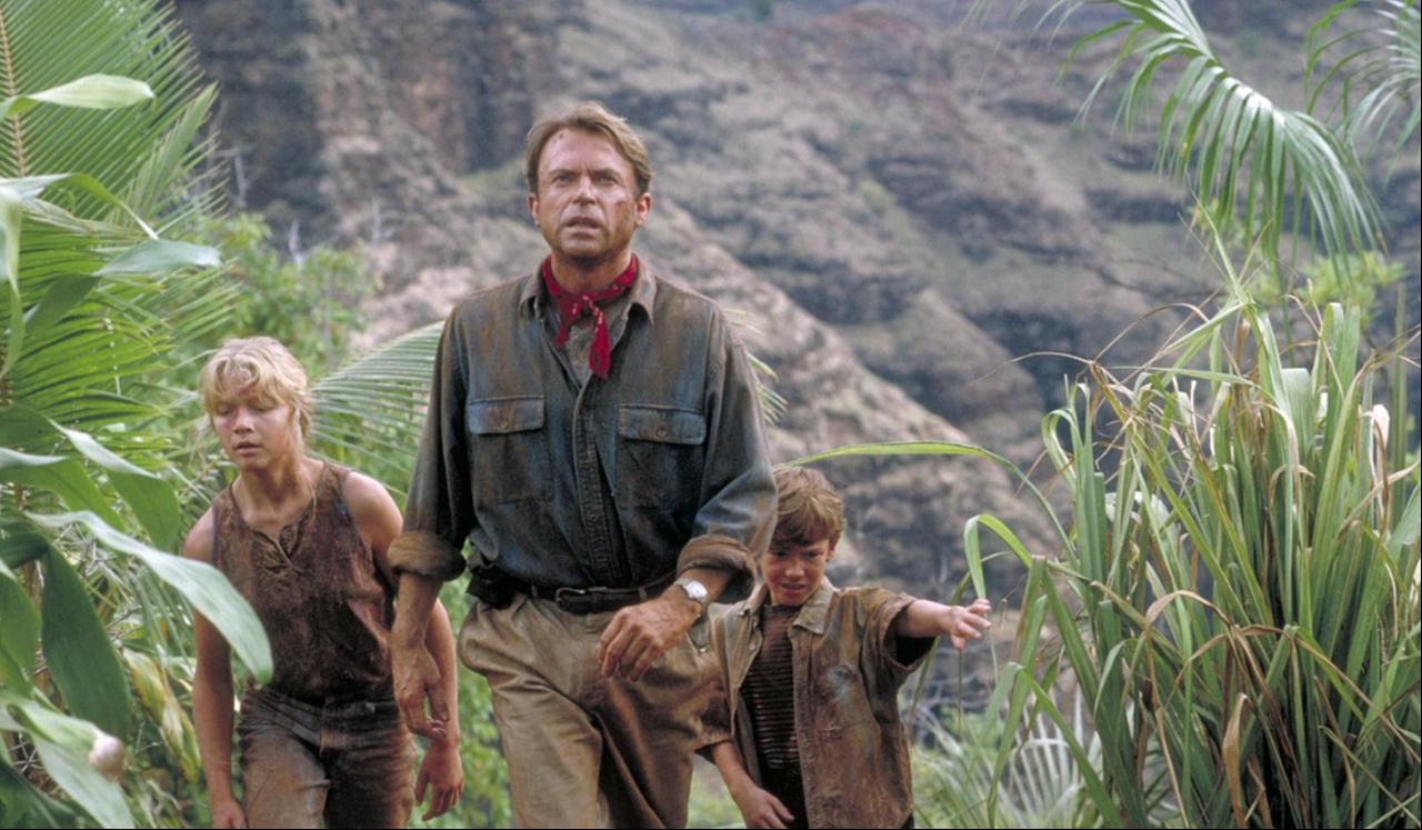 A scene from “Jurassic Park” shows three characters walking through a jungle, 1993. (Photo via IMDb)