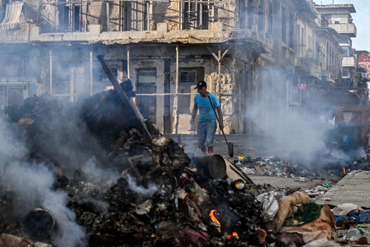 A man walks near a fire at a rubbish tip located on a street in Havana on July 14, 2026. (AFP Photo)