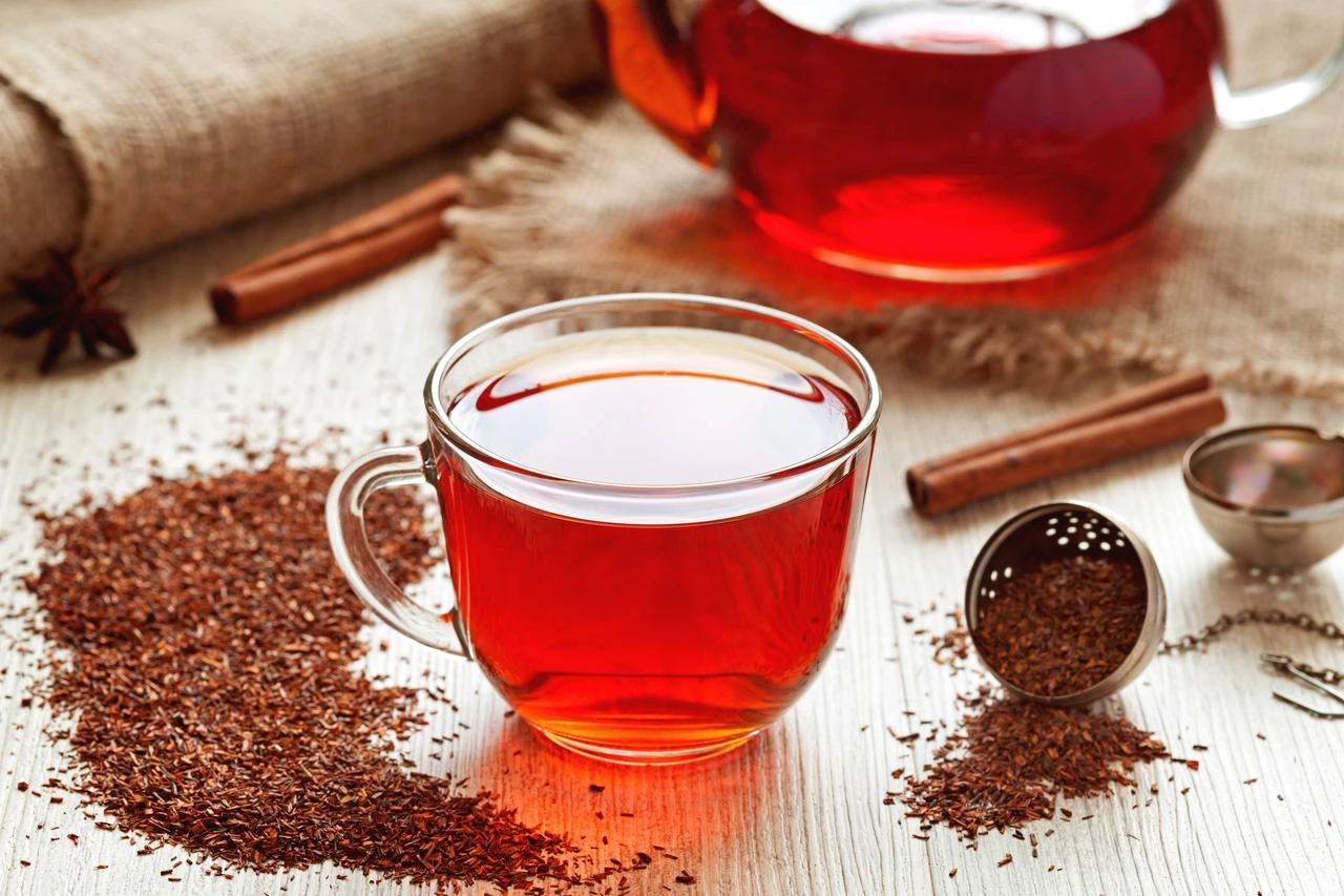Cup of healthy traditional herbal rooibos red beverage tea with spices on vintage wooden table. (Photo via Adobe Stock)