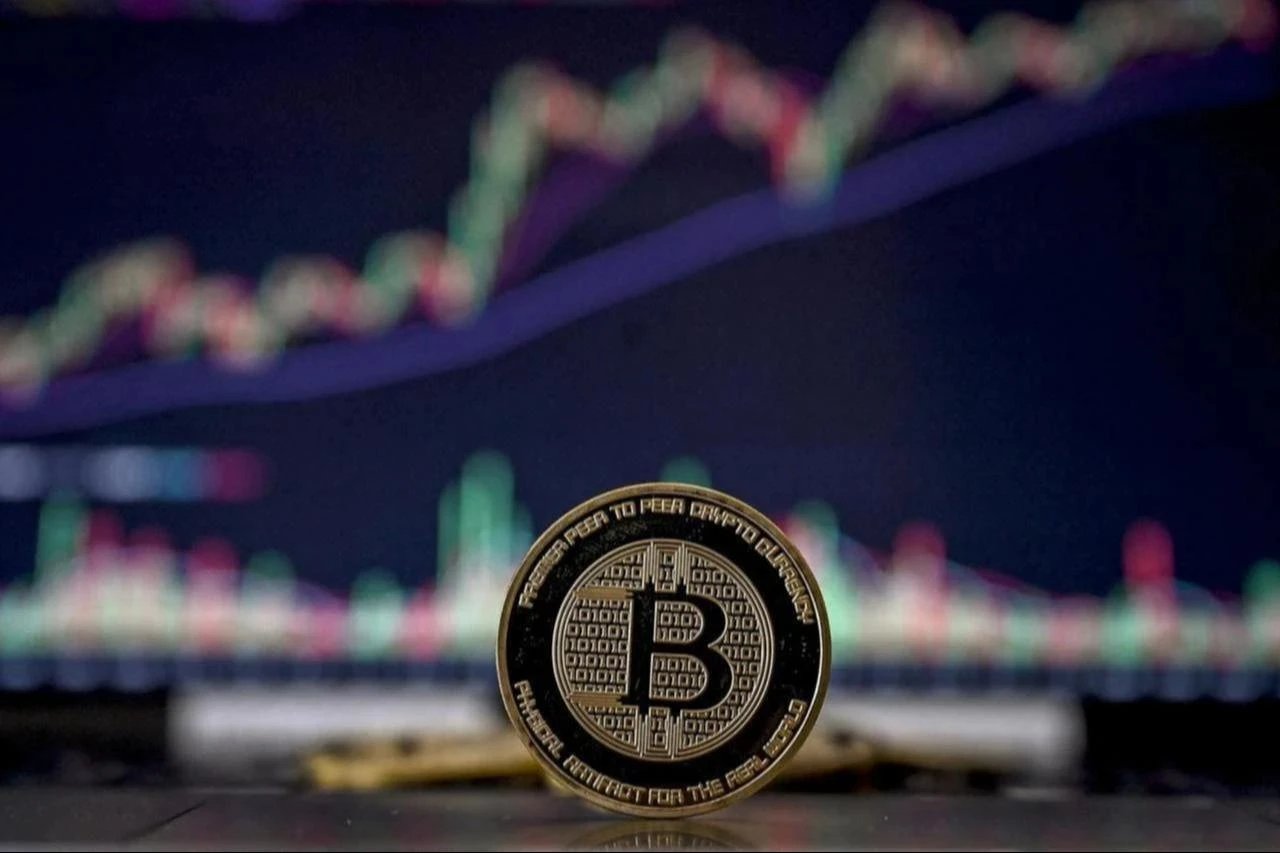 Photo illustration shows a coin imitation of the Bitcoin cryptocurrency arranged beside a screen displaying a trading chart in Istanbul, Türkiye, Nov. 22, 2024. (AFP Photo)