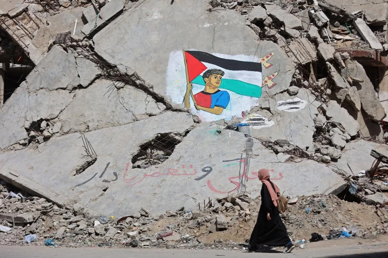 A woman walks past a mural depicting football player Lamine Yamal waving a Palestinian flag during the Catalans' title parade, painted by Palestinian artists on the rubble of buildings in Gaza City, Palestine, May 13, 2026. (AFP Photo)