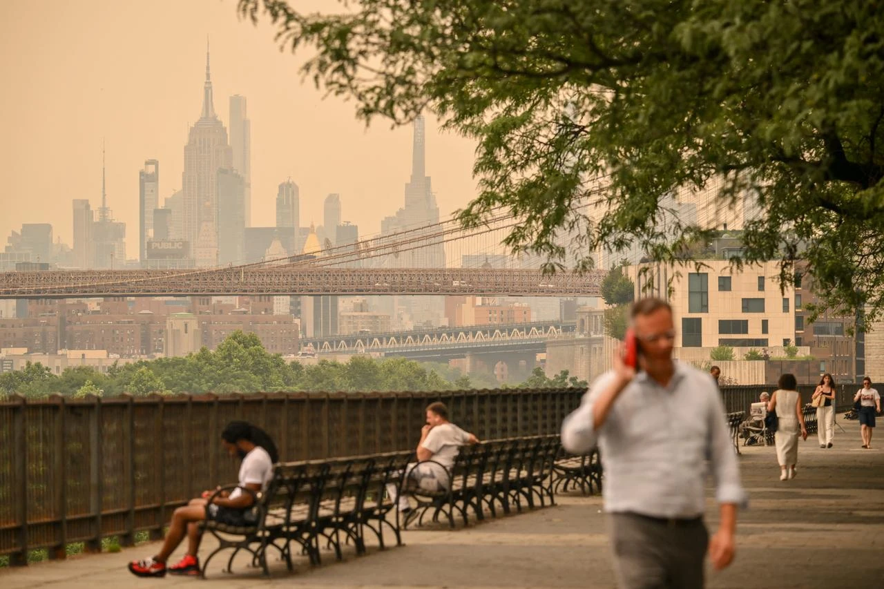 Person are seen near the Brooklyn Bridge as wildfire smoke from Canada causes hazy conditions on July 16, 2026 in New York. (AFP Photo)