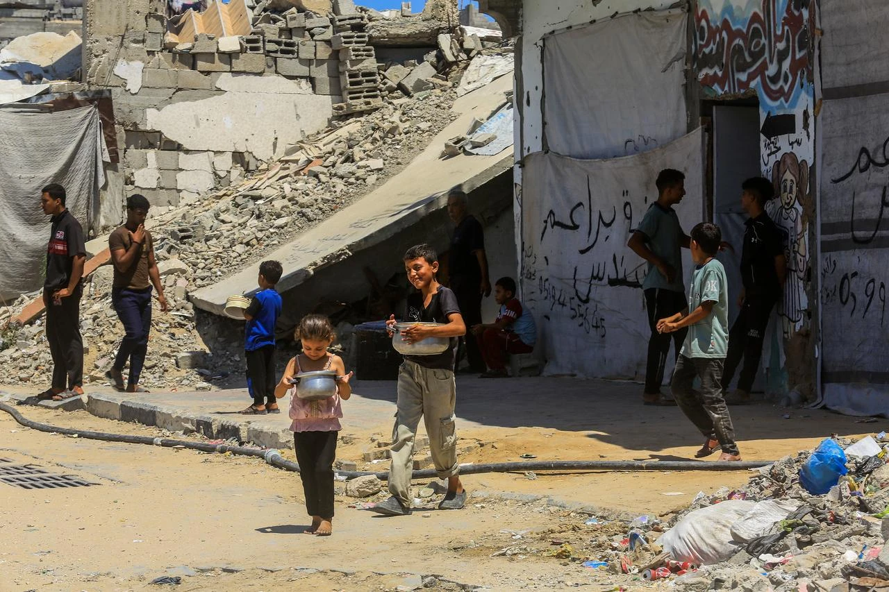 Large numbers of Palestinians, including children, gather at the distribution point to receive hot meals meals distributed by a charity in the Al-Amal neighborhood, of Khan Yunis, Gaza, Palestine on July 01, 2026. (AA Photo)