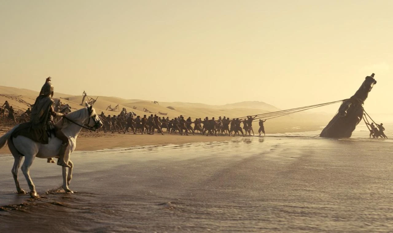 A scene from Christopher Nolan's "The Odyssey" shows a Trojan Horse-like structure being pulled along a shoreline. (Photo via IMDb)