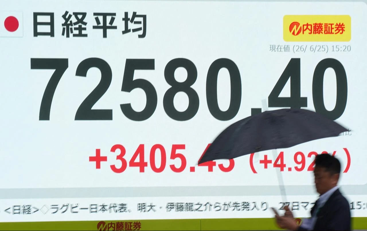 A man walks past an electronic quotation board displaying the Nikkei Stock Average on the Tokyo Stock Exchange along a street in Tokyo, June 25, 2026. (AFP Photo)