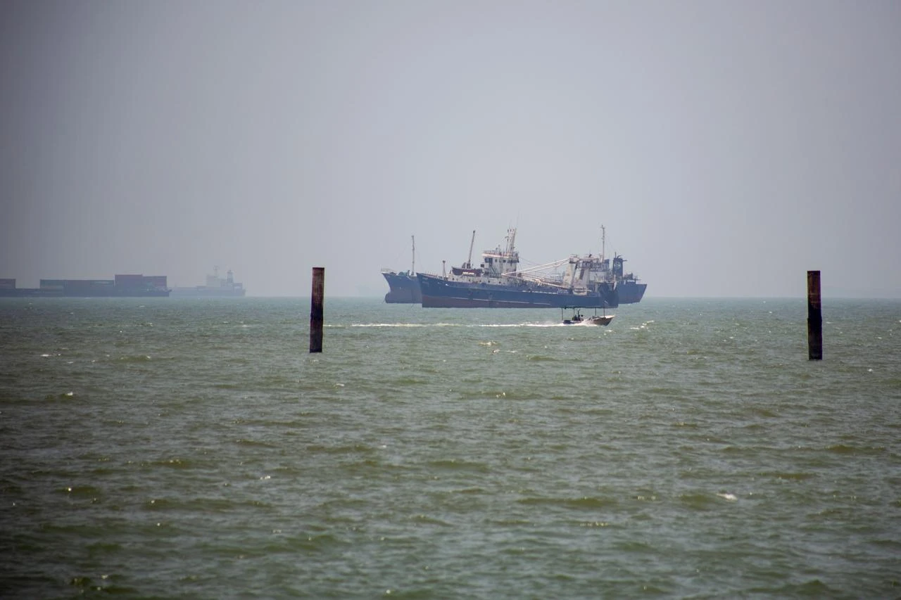 Large commercial vessels and a small boat navigate the waters off the southern port city of Bandar Abbas, Iran, June 21, 2026. (AA Photo)