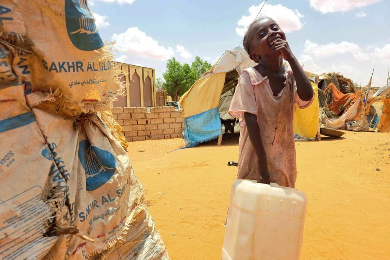 A Sudanese girl reacts while carrying a plastic canister in al-Rahmaniyah camp for displaced people, near the city of El-Obeid in the southern Kordofan region, June 25, 2026. (AFP Photo)
