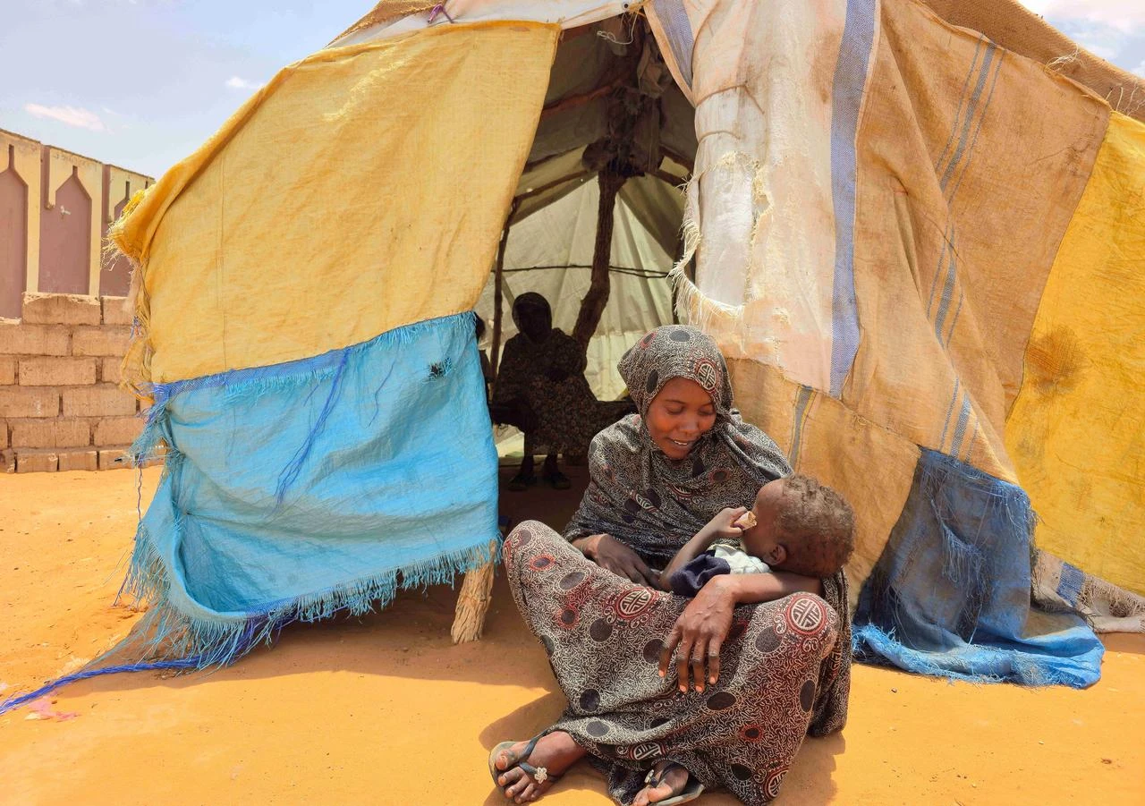 A Sudanese woman sits with her child in al-Rahmaniyah camp for displaced people, near the city of El-Obeid in the southern Kordofan region, June 25, 2026. (AFP Photo)