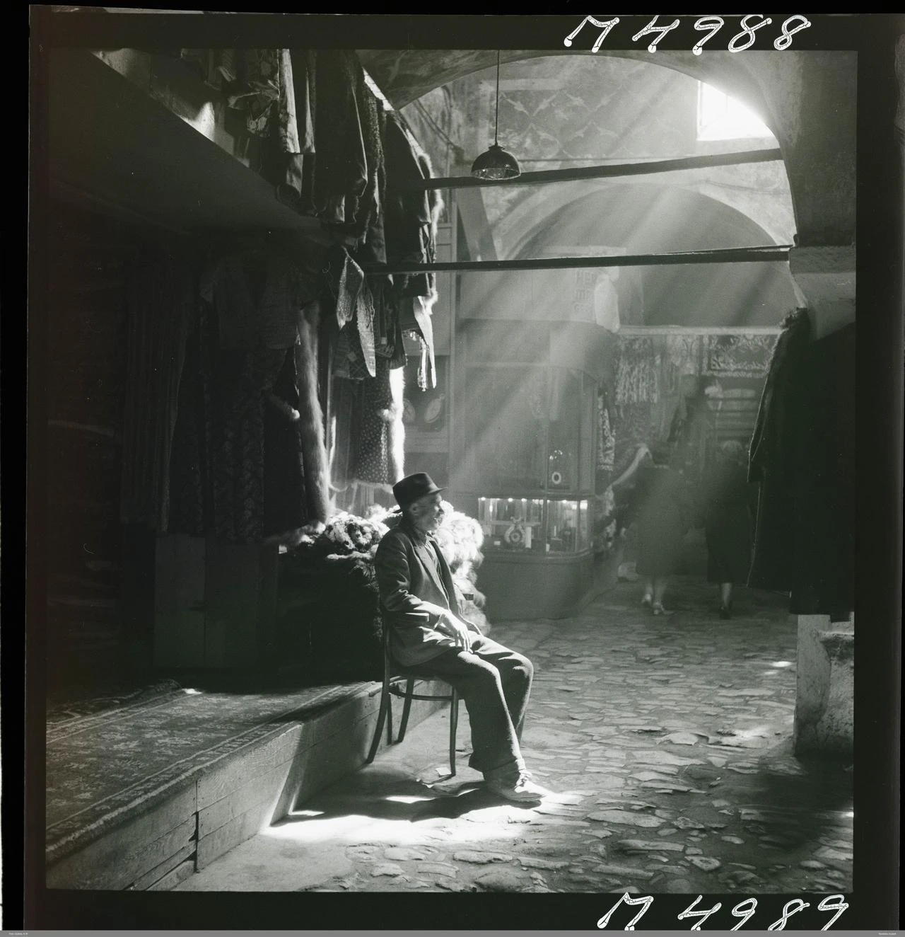 Light streaming through a window illuminates a shopkeeper sitting in front of his store. (AA Photo)