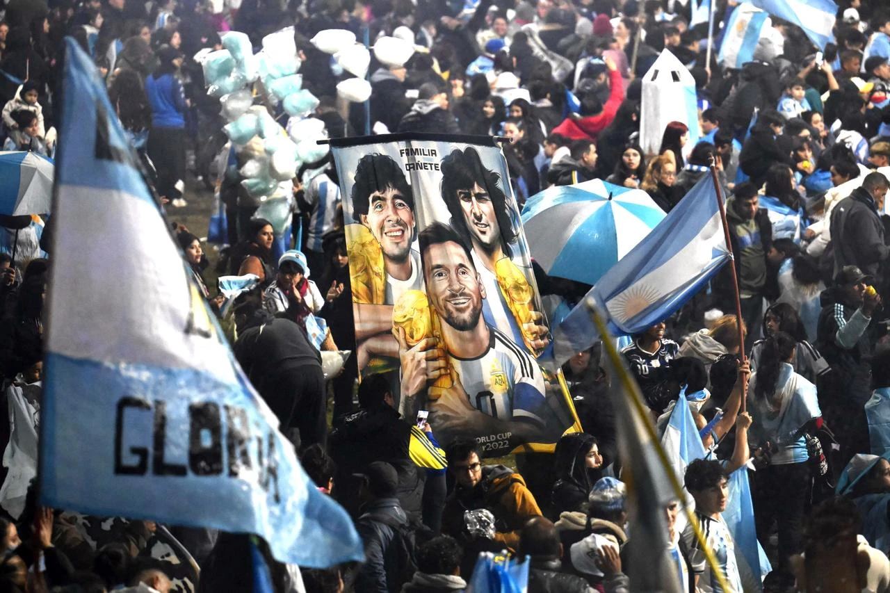 Fans hold a banner depicting Argentine football legends Diego Maradona, Mario Kempes and Lionel Messi holding FIFA World Cup trophies as supporters gather near the Argentine Football Association (AFA) training camp in Ezeiza, Buenos Aires Province, July 20, 2026. (AFP Photo)