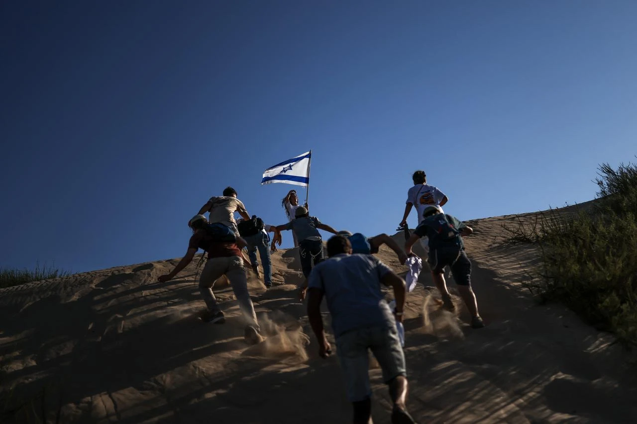 This picture taken from a position on the Israeli border with the Gaza Strip shows right-wing activists rushing up a sand dune as they attempt to make their way into the embattled territory, July 19, 2026. (AFP Photo)