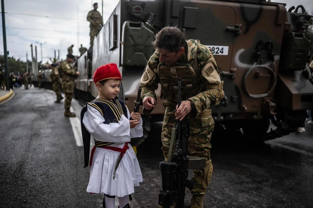 A child dressed in a traditional Greek uniform speaks with a military officer before a military parade in Athens, March 25, 2026. (AFP Photo)