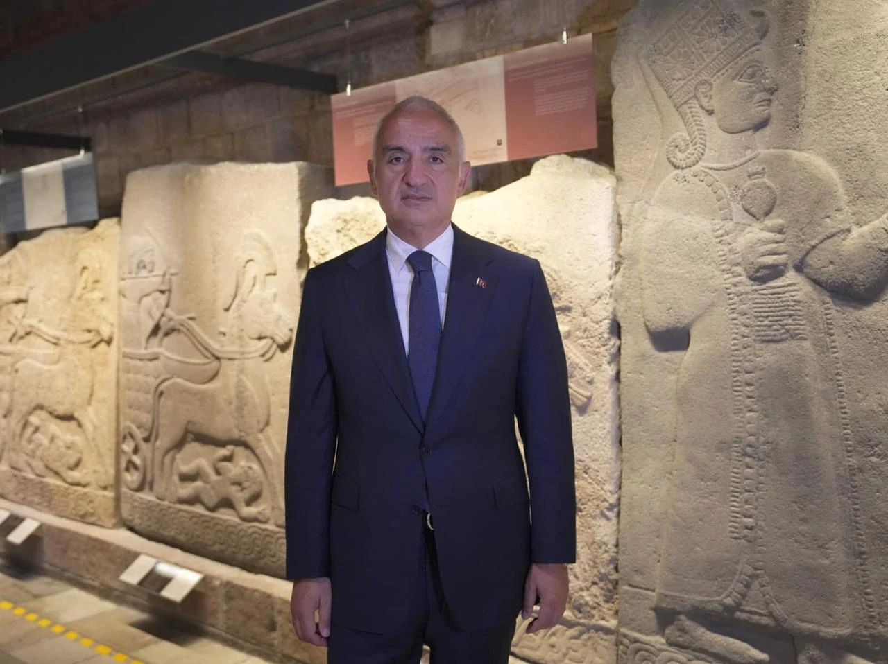 Türkiye’s Culture and Tourism Minister Mehmet Nuri Ersoy stands beside monumental stone reliefs at the Museum of Anatolian Civilizations in Ankara, Türkiye, July 21, 2026. (AA Photo)