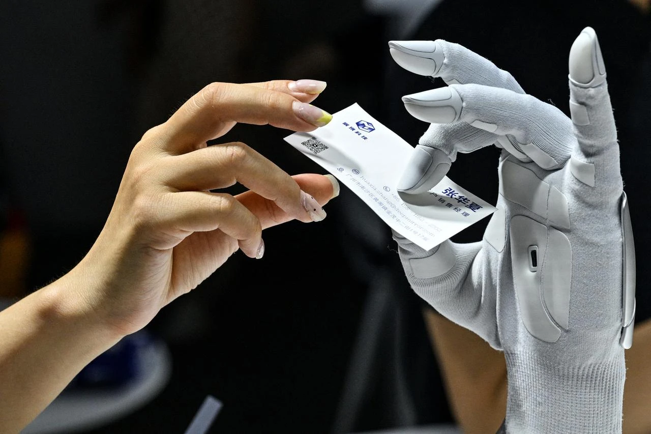 A woman gives a card to a hybrid-driver hand by Xynova Technology during the World Artificial Intelligence Conference (WAIC) in Shanghai, China, July 18, 2026. (AFP Photo)