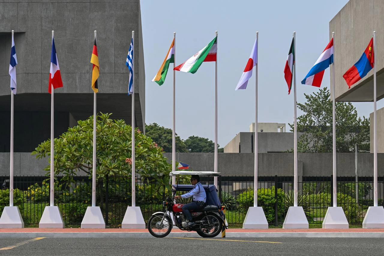A man rides past flags of ASEAN member states seen outside the venue of the 59th Association of Southeast Asian Nations (ASEAN) Foreign Ministers' Meeting and Related Meetings in Pasay, Metro Manila, July 21, 2026. (AFP Photo)