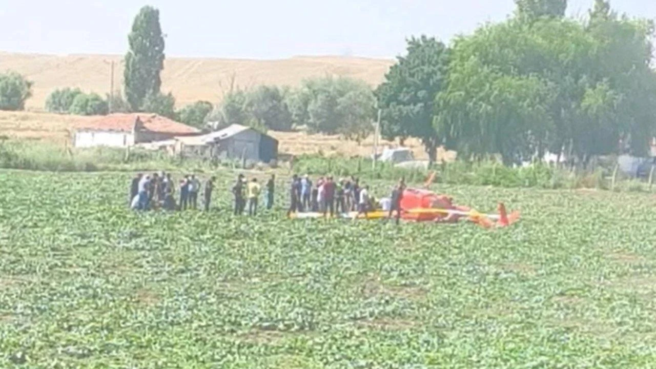 Emergency responders and bystanders gather around a training helicopter after it crashes in a field in Ankara, Türkiye, July 22, 2026. (IHA Photo)