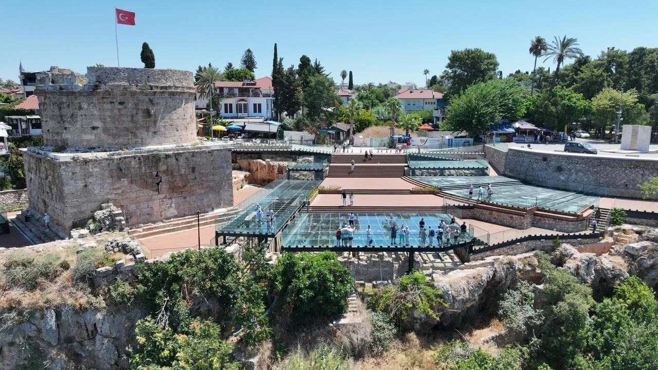 Visitors walk across glass viewing platforms beside Hıdırlık Tower following the historic site’s reopening in Antalya, Türkiye, July 21, 2026. (AA Photo)