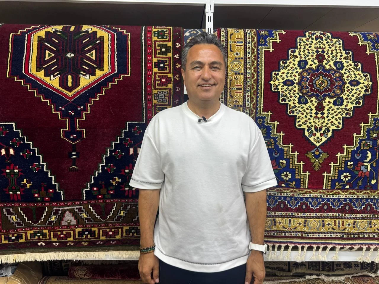 A carpet restorer poses beside antique rugs at a workshop in Istanbul, Türkiye, July 23, 2026. (AA Photo)