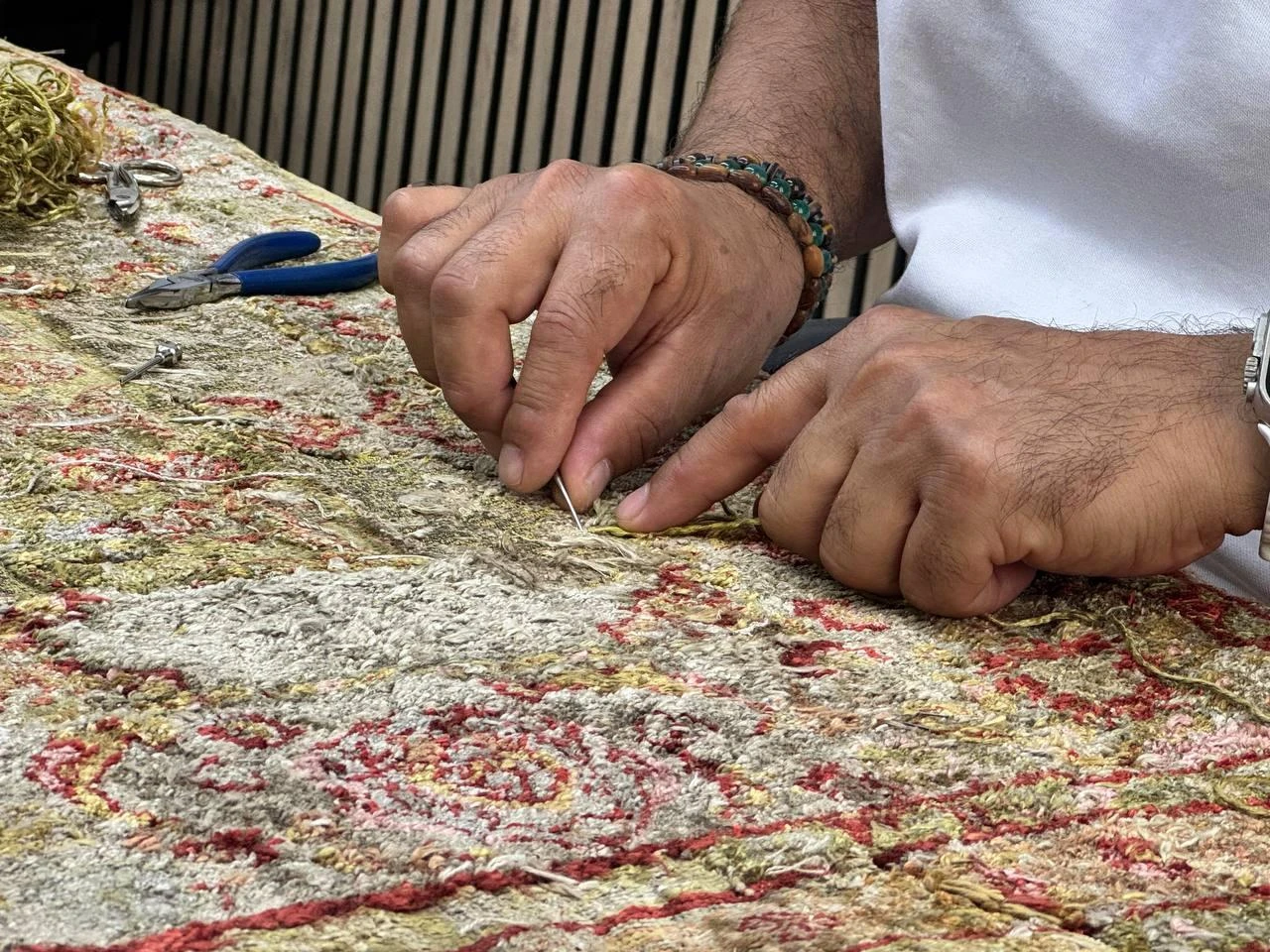 A carpet restorer repairs the worn fibers of an antique rug by hand at a workshop in Istanbul, Türkiye, July 23, 2026. (AA Photo)