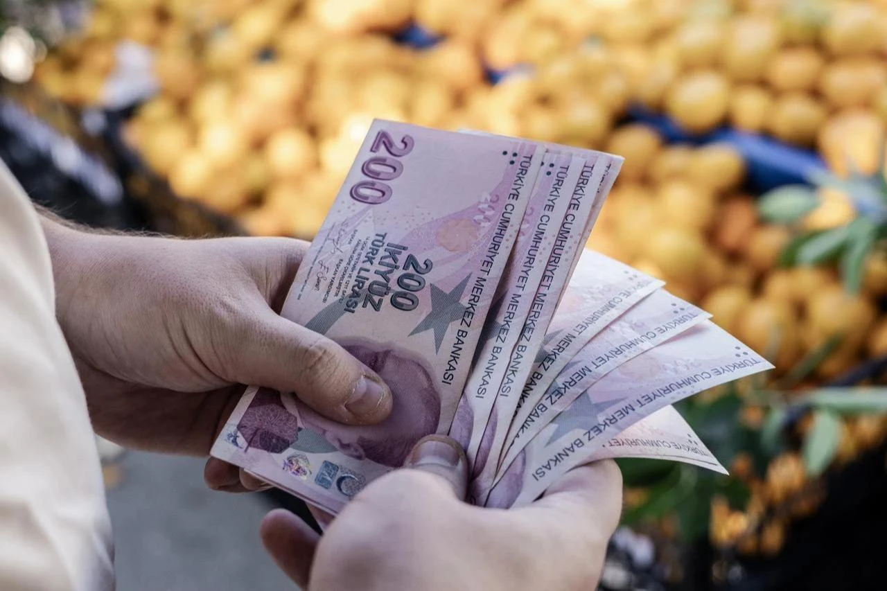 Photo shows Turkish lira banknotes in male hand against the background of vegetables at the farmers market, accessed on Nov. 20, 2025. (Adobe Stock Photo)