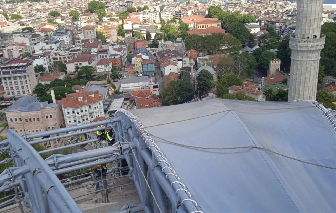 Workers secure a fire-resistant grey covering over the temporary steel roof built above Hagia Sophia’s main dome in Istanbul, Türkiye. (AA Photo)